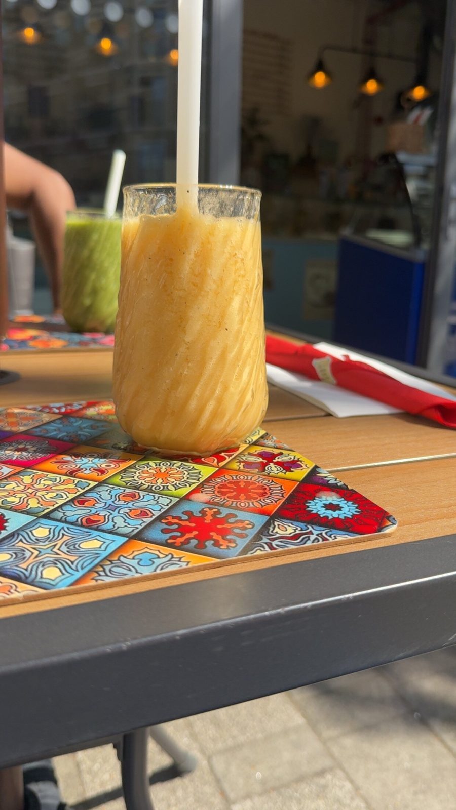 A tall mango smoothie on a patterned table