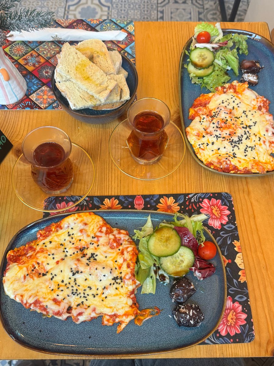 Two glasses of tea beside plates of Persian breakfast